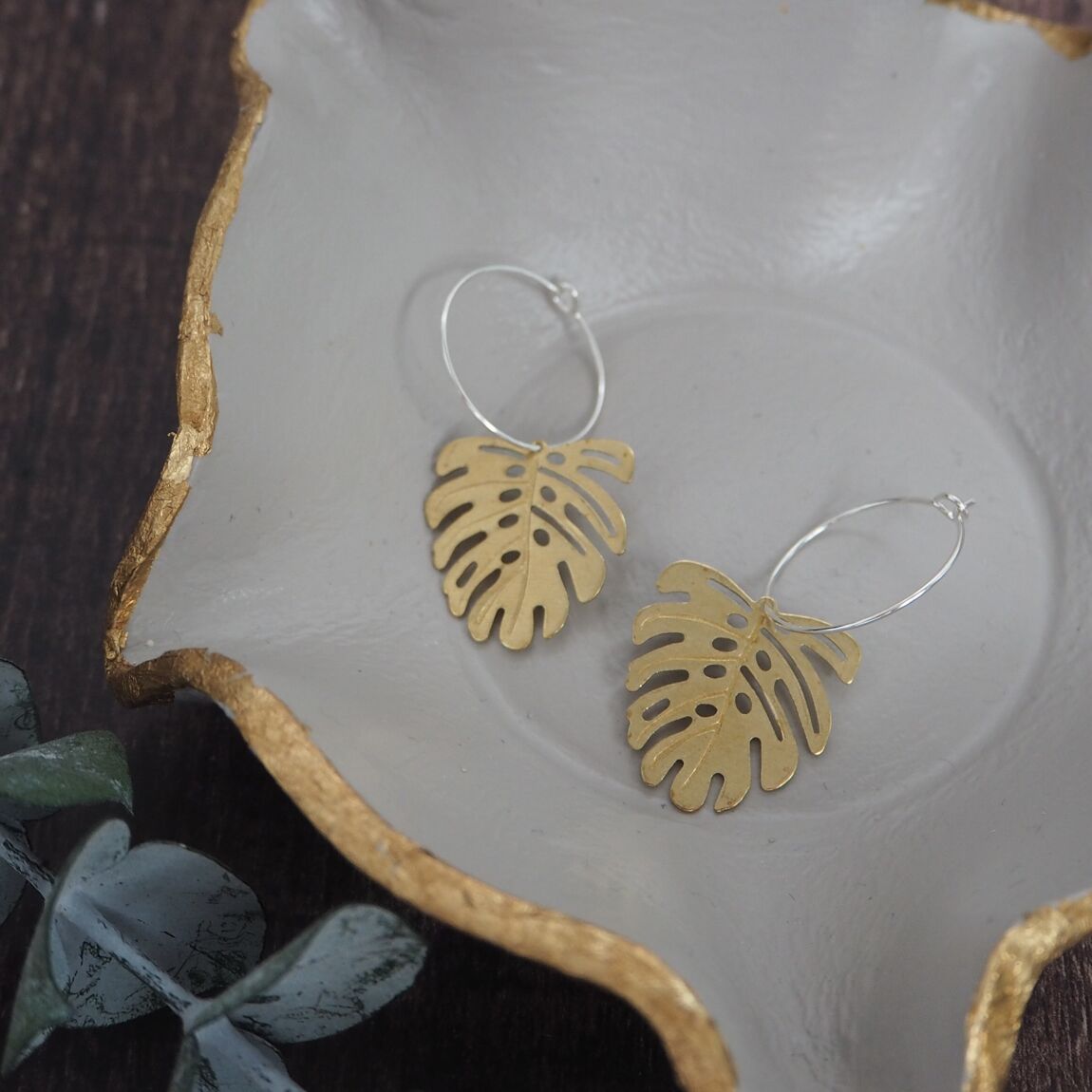 Brass monstera leaf on silver hoop earrings, a unique and stylish accessory inspired by botanical designs, available for purchase from The Petal and Plant Company.