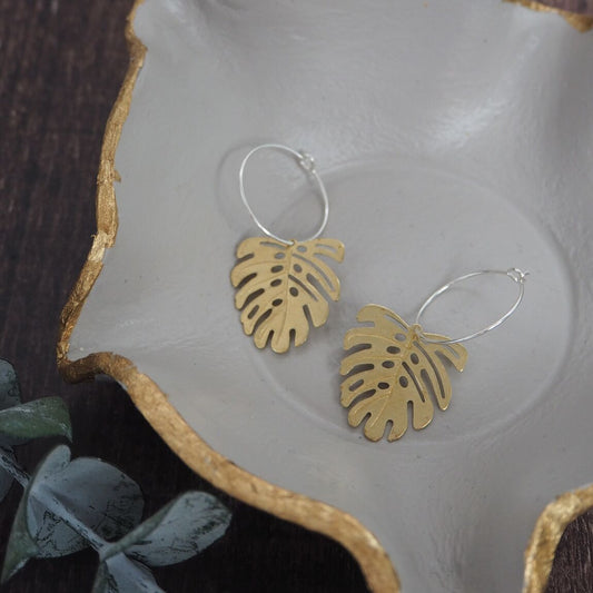 Brass monstera leaf on silver hoop earrings, a unique and stylish accessory inspired by botanical designs, available for purchase from The Petal and Plant Company.