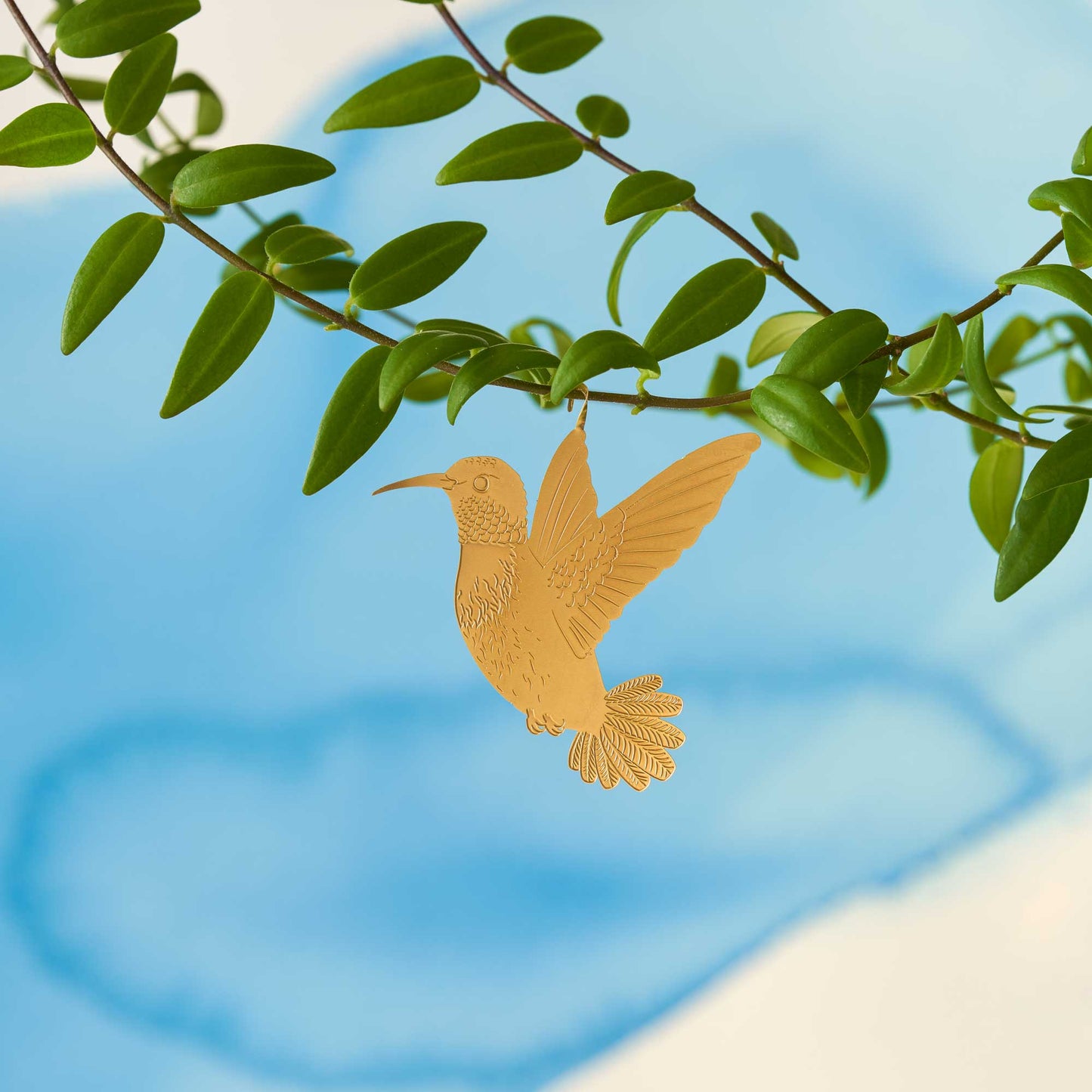 Brass hummingbird plant animal hanging from a plant, looking as if it is flying adding a playful touch to houseplants, a perfect gift for plant enthusiasts, available for purchase from The Petal and Plant Company.
