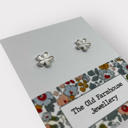 Pair of silver flower stud earrings with intricate detailing, a stylish and elegant accessory available for purchase from The Petal and Plant Company