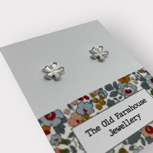 Pair of silver flower stud earrings with intricate detailing, a stylish and elegant accessory available for purchase from The Petal and Plant Company