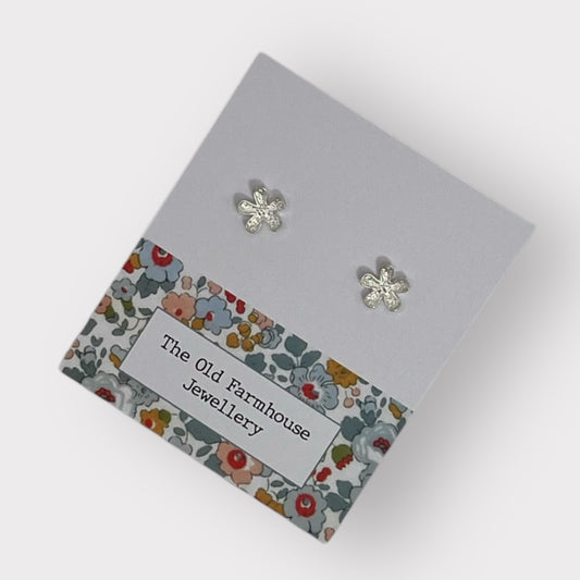 Pair of silver flower stud earrings with intricate detailing, a stylish and elegant accessory available for purchase from The Petal and Plant Company