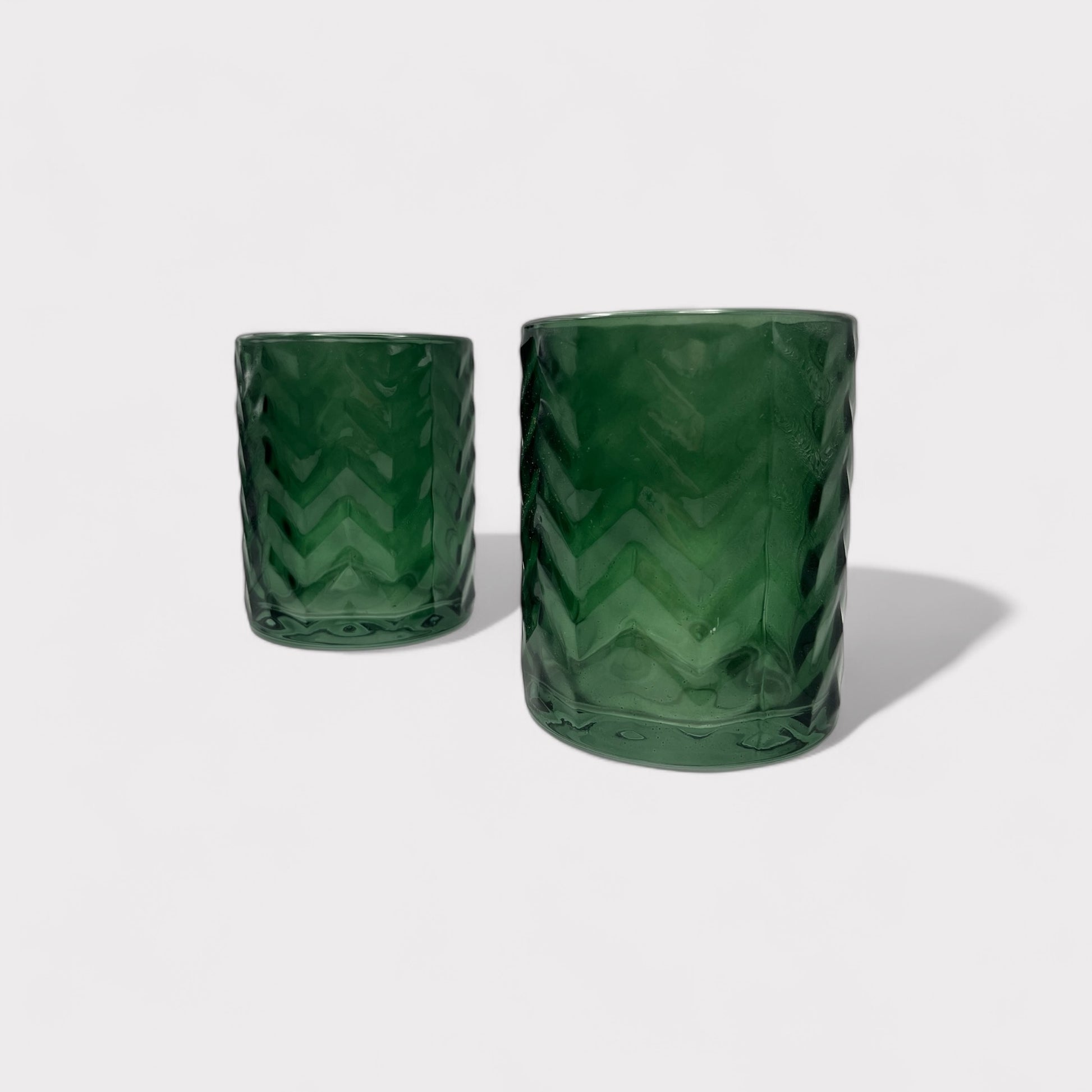 Two dark bottle green short glass vases with decorative 3D chevrons, displayed empty, perfect for floral arrangements and available for sale on The Petal and Plant Company website.