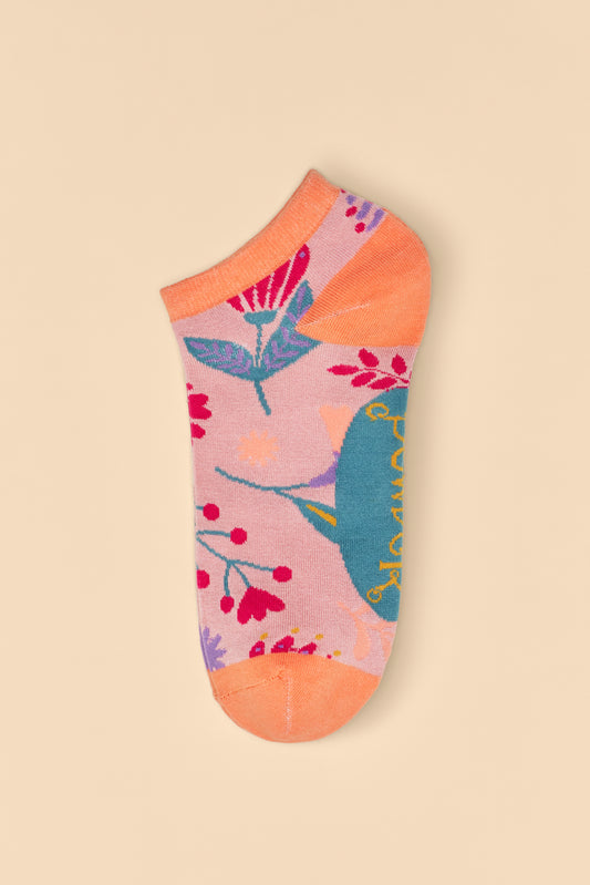 Watercolour Flowers Trainer Socks in a pink base with orange heels and toes, adorned with blue, pink, yellow, and purple floral patterns, available for purchase as a gift from The Petal and Plant Company.