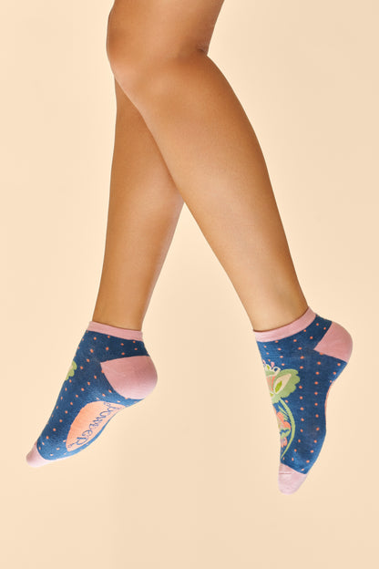 Feet wearing Scandinavian Stems Trainer Socks in navy with pale pink accents and a green flower design, a unique and cosy gift available from The Petal and Plant Company