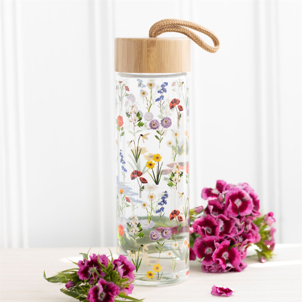 Glass reusable water bottle with a bamboo screw-top lid, featuring vibrant wildflower colour designs, an eco-friendly and stylish option available for purchase from The Petal and Plant Company