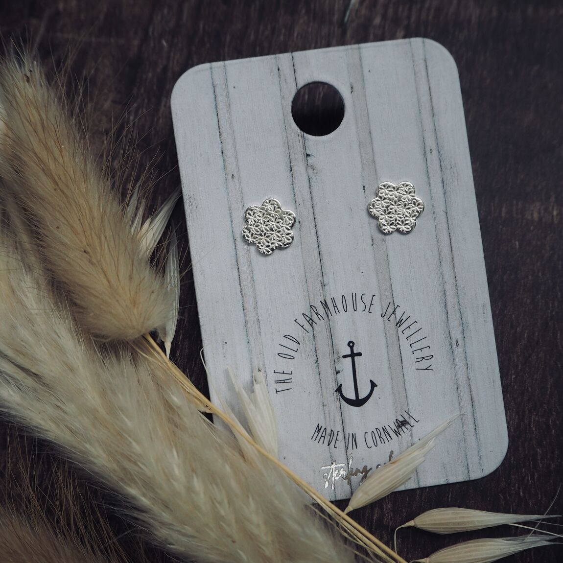 Pair of silver flower stud earrings with intricate stamped detailing, a stylish and elegant accessory available for purchase from The Petal and Plant Company